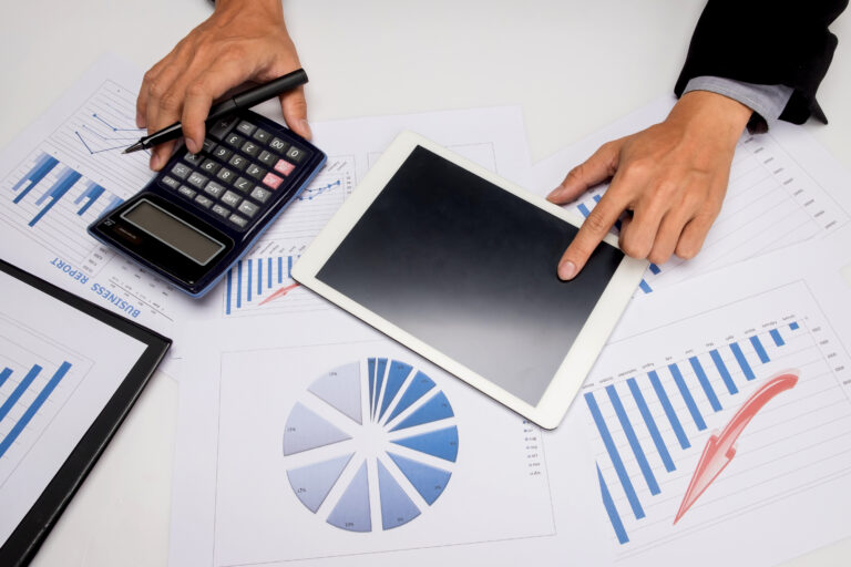 Financial advisor analyzing guaranteed lifetime income annuity illustration reports with calculator and tablet, reviewing projection charts and data for retirement planning comparison