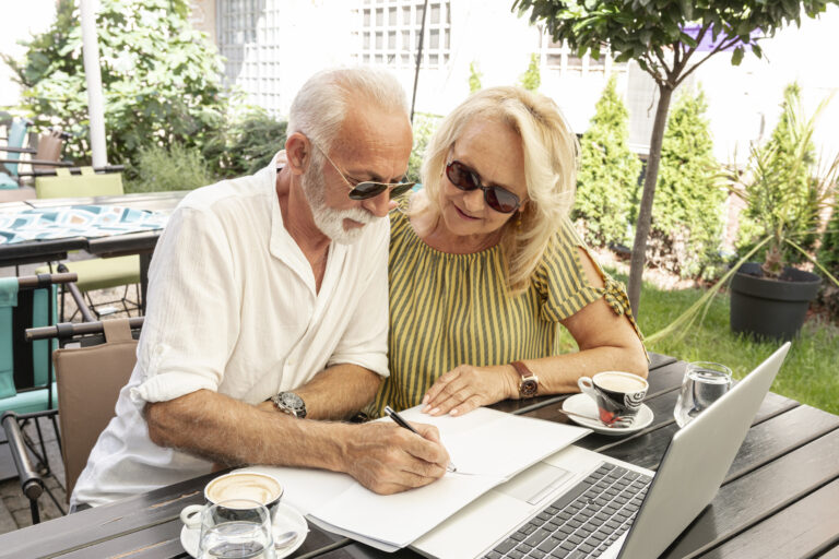 Relaxed senior couple reviewing guaranteed annuity income documents together outdoors, demonstrating peace of mind in retirement planning